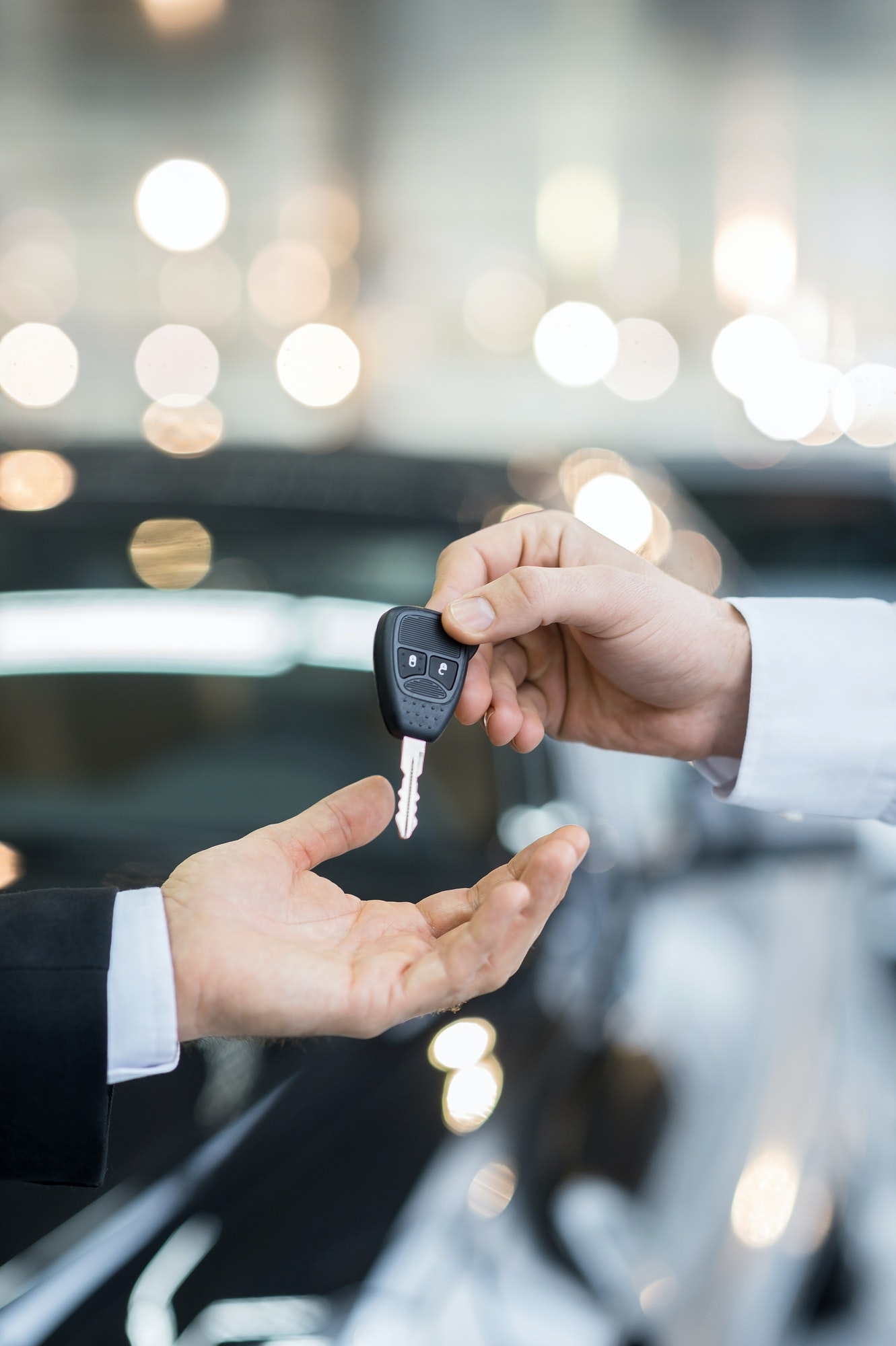 Here is your key! Close up of man giving key to the car owner while standing in front of a car